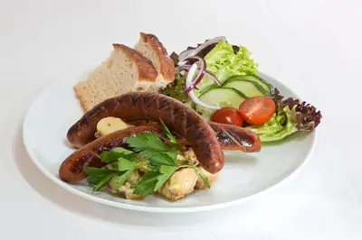 a plate of food with sausage and salad and bread at Lillehammer Hostel in Lillehammer