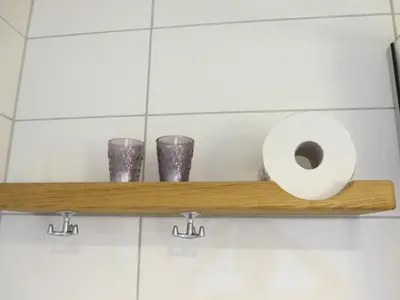 a shelf with a toilet paper and three glasses at Hamar Vandrerhjem in Hamar