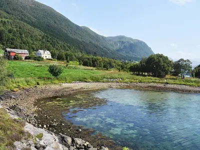 a river in a field with a house in the background at 6 person holiday home in FISKÅ-By Traum in Fiskå