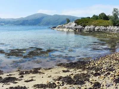 a beach with rocks and the water and mountains at 6 person holiday home in FISKÅ-By Traum in Fiskå