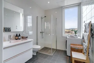 a white bathroom with a shower and a toilet at MJOS TOWER Apartment - Lovely city view in Ringsaker