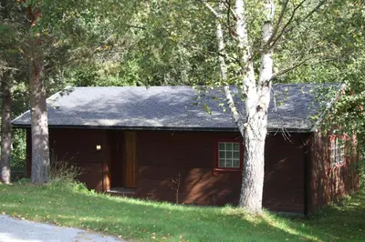 a red barn with a gambrel roof and two trees at Dovreskogen Gjestegård AS in Dovreskogen