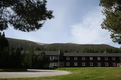 a large black building with mountains in the background at Dovreskogen Gjestegård AS in Dovreskogen