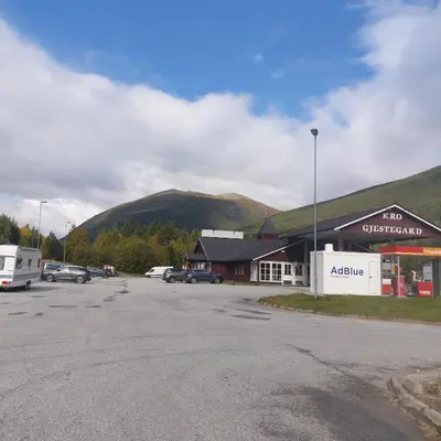 a parking lot in front of a building with a mountain at Dovreskogen Gjestegård AS in Dovreskogen