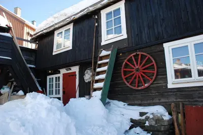 a log cabin with a red door in the snow at Regnbuegården in Røros