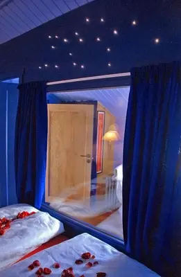 a room with two beds with blue curtains and a mirror at Regnbuegården in Røros