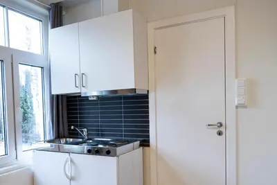 a kitchen with white cabinets and a sink and a window at Lillehammer Camping - Sentrums leilighet in Lillehammer
