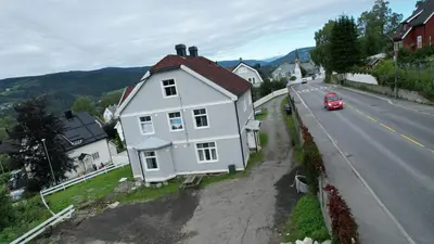 a white house on the side of a road with a red car at Lillehammer Camping - Sentrums leilighet in Lillehammer