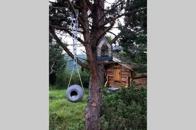 a tire swing hanging from a tree in front of a house at Fjellro Mountain Cabin in Oppdal