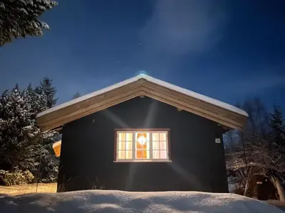 a small black house with a window in the snow at Fjellro Mountain Cabin in Oppdal