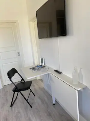 a white desk with a chair and a television on a wall at Feriehus med Sjøutsikt in Sætra