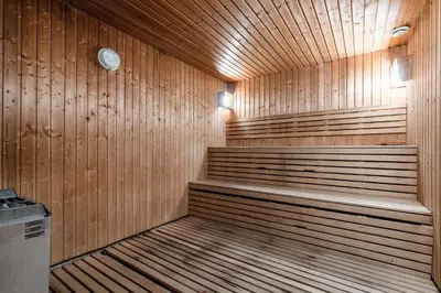a wooden sauna with benches and a clock in it at Ustedalen Resort Leiligheter in Geilo
