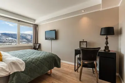 a bedroom with a bed and a desk and a television at Ustedalen Resort Leiligheter in Geilo