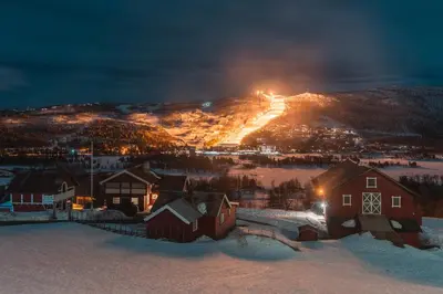 a town in the snow at night with lights on a mountain at Ustedalen Resort Leiligheter in Geilo