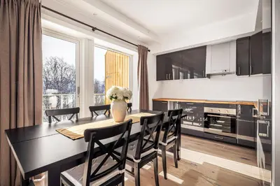 a dining room with a table and chairs and a kitchen at Ustedalen Resort Leiligheter in Geilo