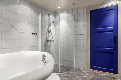 a bathroom with a tub and a blue door at Kirkebøen Hytter in Hemsedal