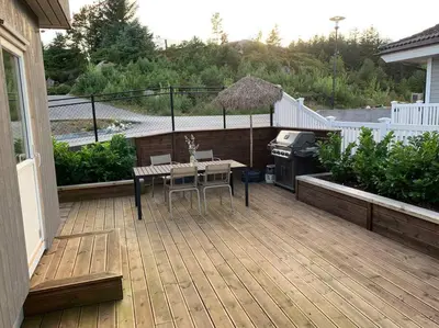 a patio with a table and a grill on a deck at Villa with jacuzzi in Nord Bjørøy