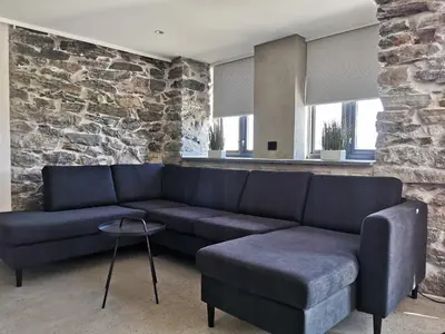 a living room with a blue couch and a stone wall at Godo Lodge in Godøy