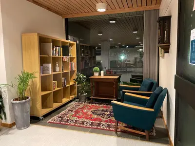 a library with two chairs and a table and bookshelves at BORG Sommerhotell in Ålesund