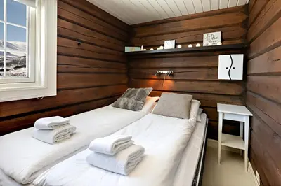 two beds in a room with wooden walls at Utsikten in Sykkylven