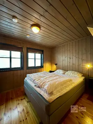 a bed in a room with a wooden ceiling at Large cabin at Sjusjøen with sauna, fireplace, view and cross-country skiing in Ringsaker