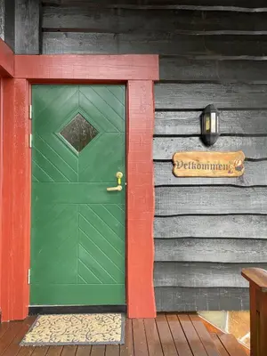 a green door on the side of a house at Large cabin at Sjusjøen with sauna, fireplace, view and cross-country skiing in Ringsaker