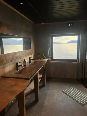 a bathroom with a sink and two windows at Hjelvikhytta - flott beliggenhet ved sjøen in Hjelvik