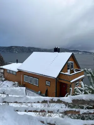 a house with snow on top of it at Hjelvikhytta - flott beliggenhet ved sjøen in Hjelvik