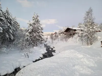 a river covered in snow in front of a house at Øen Turistsenter Apartments in Geilo