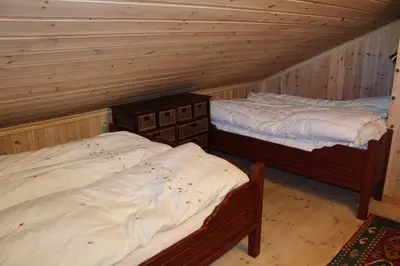 two twin beds in a room with wooden walls at Magnesplass - Dagalifjell in Dagali