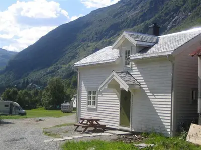 a white house with a picnic table in front of a mountain at Seim Camping - Røldal in Røldal