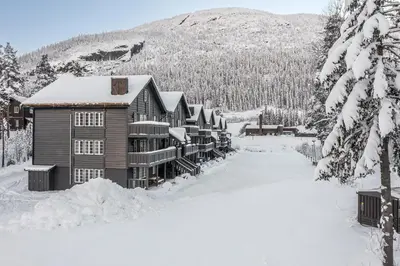 a lodge in the snow with snow covered trees at Tinden Apartments in Hemsedal