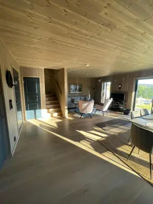 a living room with a wooden ceiling and a table and chairs at Geilo - Ny og flott hytte på budalstølen in Geilo