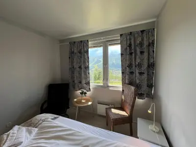 a bedroom with a bed and a window with a chair at Hallingskarvet Fjellstue as in Hovet