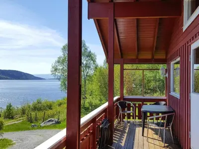 a red house with a balcony with a view of the water at 6 person holiday home in VATNE-By Traum in Vatne