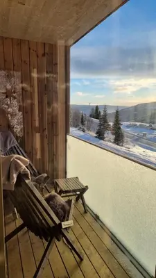a rocking chair on a deck with a large window at Cozy Apartment by the slopes in Kvitfjell Vest in Favang