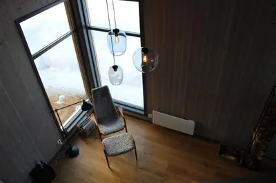 a room with a chair and a window and a chandelier at Skarvhytta - moderne hytte med flott beliggenhet in Hol