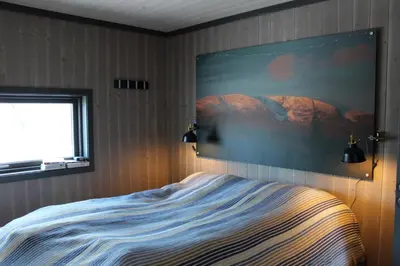a bedroom with a bed with a painting on the wall at Skarvhytta - moderne hytte med flott beliggenhet in Hol