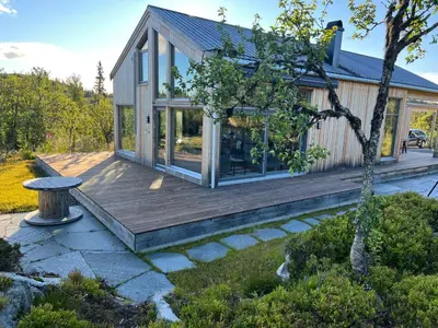 a home with a wooden deck and a tree at Skarvhytta - moderne hytte med flott beliggenhet in Hol