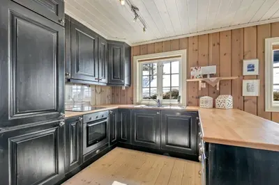 a kitchen with black cabinets and a wooden floor at Gaustablikk hytta ski-in ski-out in Gaustablikk