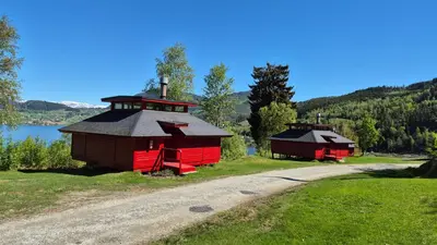 two red buildings on a field next to a road at Kvamshaugen hytter in Luster