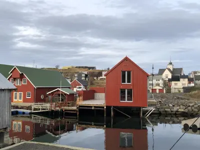 a red house on the water in a small town at Robinsons Rorbu - located in Bud in Bud