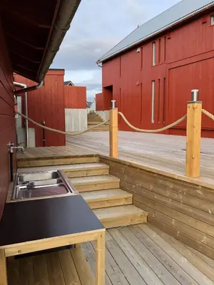 a wooden deck with stairs next to a red building at Robinsons Rorbu - located in Bud in Bud