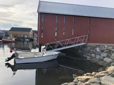 a boat in the water next to a red building at Robinsons Rorbu - located in Bud in Bud
