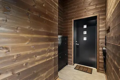 a hallway with wooden walls and a black door at Ski in ski out mountain cabin with views and extra unit option in Sogndal