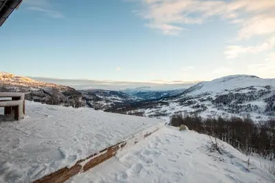 a winter view of a snowy mountain with a bench at Ski in ski out mountain cabin with views and extra unit option in Sogndal