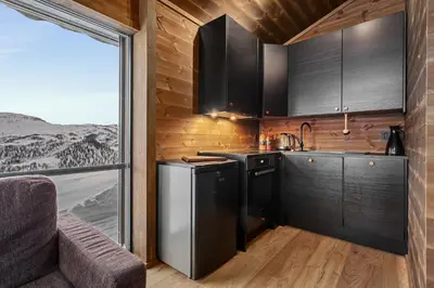 a kitchen with black cabinets and a large window at Ski in ski out mountain cabin with views and extra unit option in Sogndal