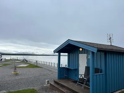 a blue shack with a chair sitting on a dock at Kviltorp Camping in Molde