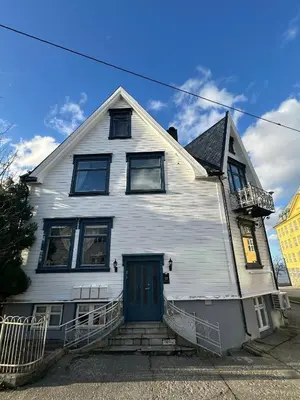 a white house with a blue door on a street at Downtown Historical House with Renovated apartments free P near in Ålesund