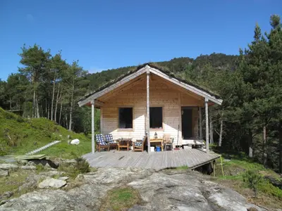 a log cabin with a wooden deck in the woods at Chalet Svanöy by Interhome in Grimeli